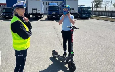 Policjantka sprawdza, czym można jeździć na kartę rowerową. Chłopiec zakłada kask na hulajnogę elektryczną.