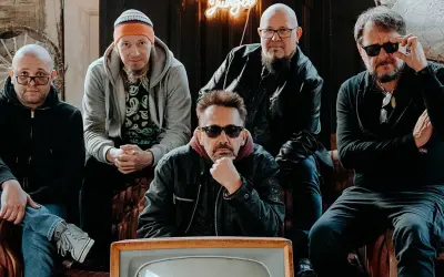 Pięciu mężczyzn, zespół Sztywny Pal Azji, siedzi na kanapie. W tle neonowy napis "Jungle".