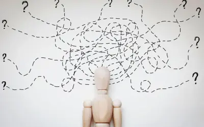 Drewniany manekin z chaotycznymi liniami i znakami zapytania nad głową, symbolizującymi trudności w diagnozie, np. borderline ICD 10.