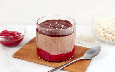 Choklad overnight oats med hallon och en sked redo att avnjutas.