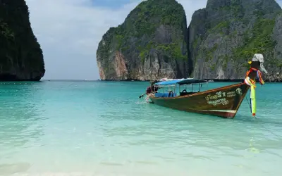 Łódź kołysze się na turkusowych wodach Maya Bay, otoczonej stromymi, porośniętymi zielenią klifami.