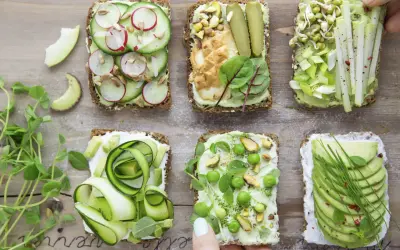 Sześć pysznych kanapek z awokado, ozdobionych warzywami, kiełkami i orzechami. Idealne na zdrowy lunch!
