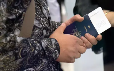 Ręce trzymają paszport i bilet lotniczy. Widoczne są dane do biletu lotniczego, takie jak numer lotu i bramka.