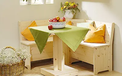 Holzige Eckbank mit Schlaffunktion selber bauen: Gemütliche Sitzecke mit Tisch, Äpfeln und Blumenkorb.