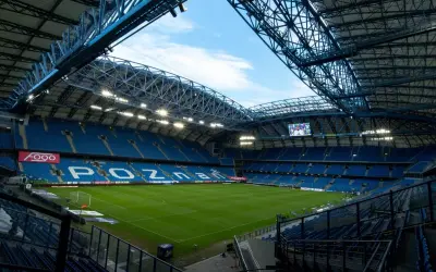 Pusta, błękitna trybuna stadionu Lecha Poznań, gotowa na przyjęcie kibiców. Pojemność stadionu robi wrażenie.