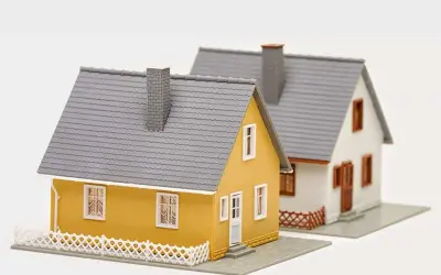 Dwa domki modelowe. Jeden żółty, drugi biały. Budowa domu w granicy działki wymaga zgody sąsiada.