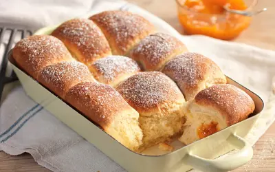 Frisch gebackene Buchteln, bestäubt mit Puderzucker, warten darauf, mit Marillenmarmelade gefüllt zu werden. Ein echtes Buchteln original Rezept.