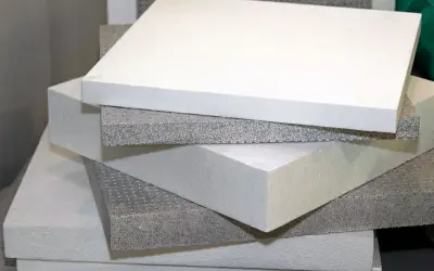 Pannelli bianchi e grigi di piastrelle isolanti termiche impilati, pronti per l'isolamento edilizio.