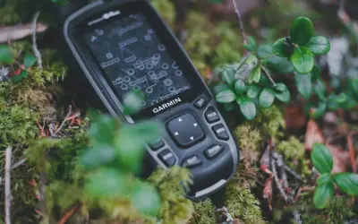 Garmin inReach, jako akcesoria do komunikacji satelitarnej, leży na mchu w lesie.