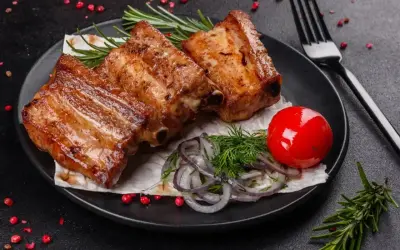 Soczyste żeberka z grilla, podane z pomidorkiem, cebulką i ziołami. Idealne na letnie wieczory.