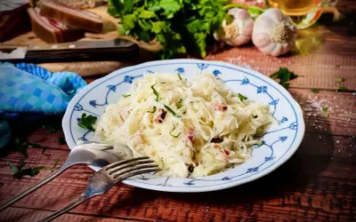 Herzhaftes Krautsalat Rezept mit Speck und frischen Kräutern, serviert auf einem blauen Tellerchen. Dazu Brot, Knoblauch und Petersilie.