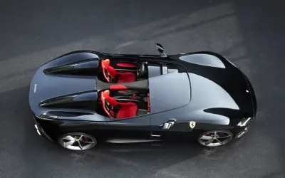 Czarny Ferrari Monza SP1 z czerwonymi siedzeniami, gotowy do jazdy po torze.