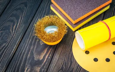 Outils de ponçage : brosse métallique, éponges abrasives et papier de verre pour préparer une surface en polyester avant l'application d'époxy.
