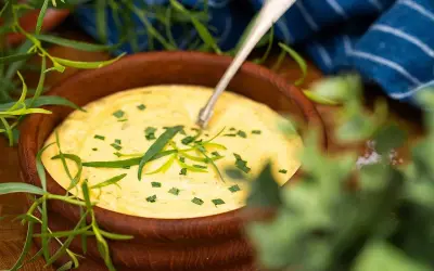 Krämig bearnaisesås i träskål, perfekt för ett enkelt bearnaisesås recept med stavmixer. Garnerad med färsk dragon.