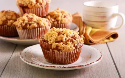 Pyszne muffinki drożdżowe z kruszonką na talerzykach, obok filiżanka kawy.