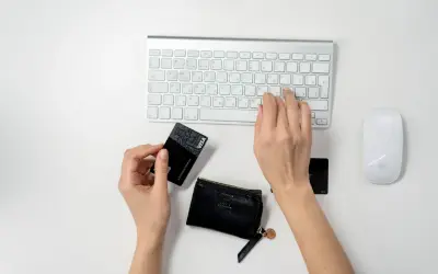 Ręce wpisują dane karty płatniczej na klawiaturze, przygotowując się do transakcji online. To pierwszy krok, jak zacząć sprzedawać w internecie.