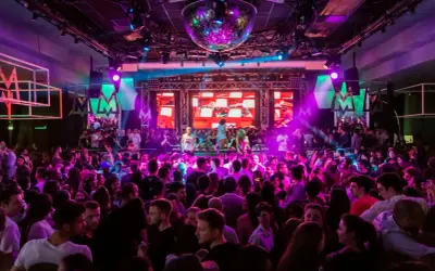 En stor publik njuter av 30 års fest aktiviteter med DJ och discokula. Ljusshow i lila och rosa skapar en festlig stämning.