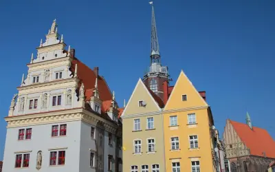 Kolorowe kamienice i wieża kościelna na rynku w Nysie pod błękitnym niebem.