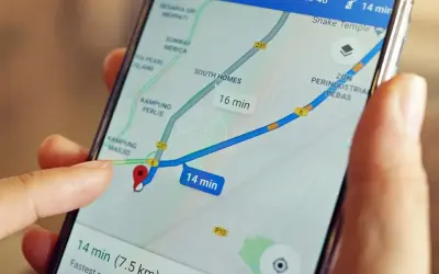Palec dotyka ekranu smartfona z mapą, pokazując trasę i czas dojazdu. Dowiedz się, jak wysłać pinezkę, by udostępnić lokalizację.