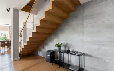 Nowoczesne schody dywanowe z drewna dębowego, szklana balustrada i beton architektoniczny tworzą elegancką przestrzeń.