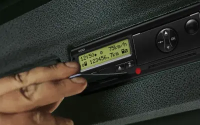 Une main insère une carte dans un tachygraphe intelligent VDO affichant 75 km/h et 23456.7 km.