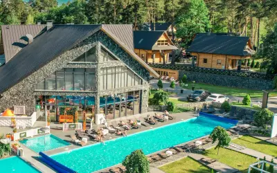 Hotel Bacówka Radawa: basen, leżaki i drewniane domki w otoczeniu lasu.