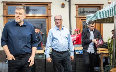 Mężczyźni w garniturach i koszulach, jeden z nich trzyma materiały wyborcze Lewicy.