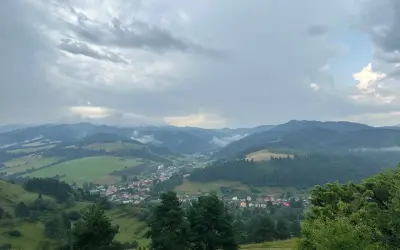 Widok na dolinę z wioską i górami w tle, chmury nad przełęczą pod Tokarnią.