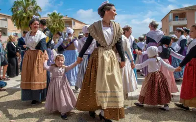 Un groupe danse en cercle, portant une tenue traditionnelle française homme et femme, avec des coiffes et des jupes colorées.