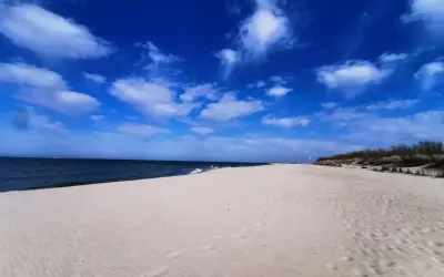 Piękny, pusty piasek i błękitne niebo z chmurami. Idealne miejsce na wyjazd nad morze.