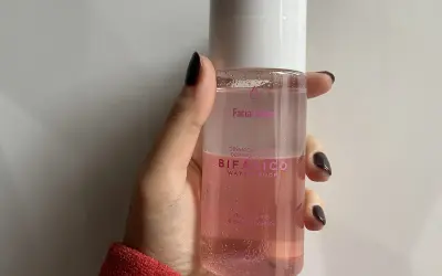 Mano sujetando un agua micelar rosa Bifásico de Mercadona, ideal para desmaquillar ojos y labios.