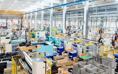Nowoczesna hala produkcyjna z liniami maszyn, robotami i taśmociągami. Efektywne zarządzanie produkcją w akcji.