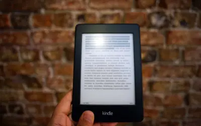 Dłoń trzyma czytnik Kindle z tekstem. Komputer nie widzi Kindla, mimo że jest podłączony.