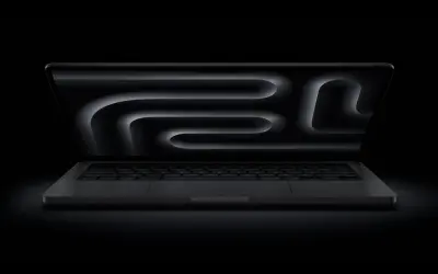 MacBook Pro z polskim układem klawiatury, ciemny ekran z abstrakcyjnym wzorem.