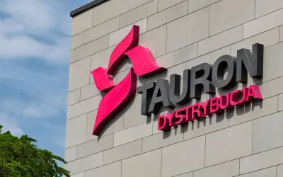 Logo Tauron Dystrybucja na szarej ścianie budynku. Zwiększenie mocy przyłączeniowej Tauron to klucz do rozwoju.