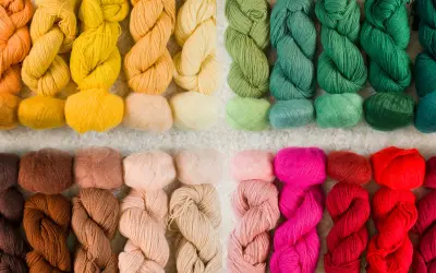 Ett urval av garn i olika färger, från varma orange och gula toner till gröna, rosa och röda nyanser. Perfekt för ditt nästa projekt med garn lin.