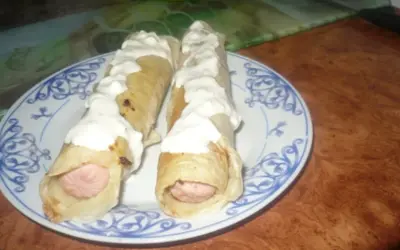 Dwa parówki w cieście naleśnikowym, polane sosem. Pyszna przekąska na szybko.