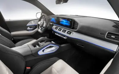 Interior de un Mercedes moderno, con pantallas digitales, asientos de cuero y detalles de iluminación ambiental azul.