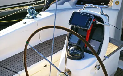 Cockpit de voilier avec barre, compas et écran Raymarine. Idéal pour un gps marine gratuit pour Android.