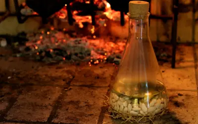 Fagioli al fiasco, un'antica ricetta che profuma di camino e tradizione. I fagioli bianchi riposano in un fiasco di vetro, pronti per essere cotti lentamente.