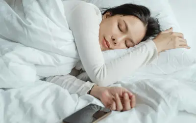 A woman sleeps peacefully, perhaps a natural short sleeper, with her phone nearby.