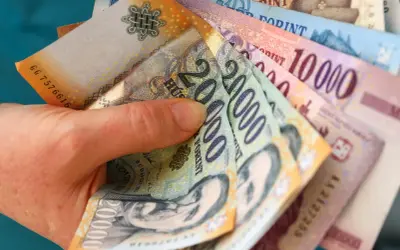 Dłoń trzyma stos węgierskich forintów. Zastanawiasz się, gdzie wymienić forinty? Warto sprawdzić kursy w kantorach lub bankach.