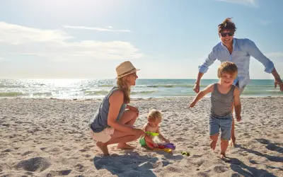 Rodzina cieszy się rodzinnymi atrakcjami na plaży. Dzieci bawią się piaskiem, a rodzice patrzą z uśmiechem.