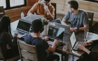 Grupa osób pracuje przy laptopach, dyskutując o regulaminie pracy.