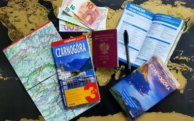 Pasport, pieniądze i przewodniki po Czarnogórze leżą na mapie świata. Czy do Czarnogóry potrzebny jest paszport? Tak, polski paszport jest widoczny.