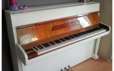 Białe pianino z drewnianymi elementami. Zastanawiasz się, ile kosztuje strojenie pianina?