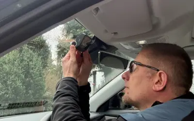 Mężczyzna montuje kamerę samochodową nad lusterkiem wstecznym. Dbałość o szczegóły podczas instalacji zapewnia bezpieczeństwo na drodze.