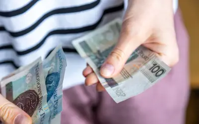 Ręce liczą banknoty 100 zł. Czy za mieszkanie komunalne się płaci? Tak, czynsz jest obowiązkowy.