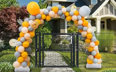 Jak samemu zrobić stojak na balony? Łuk z pomarańczowych, szarych i białych balonów nad bramką.