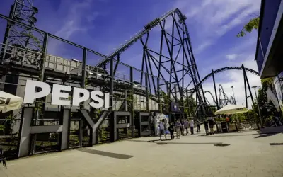 Energylandia opinie: ogromna kolejka górska Pepsi z ludźmi w tle.